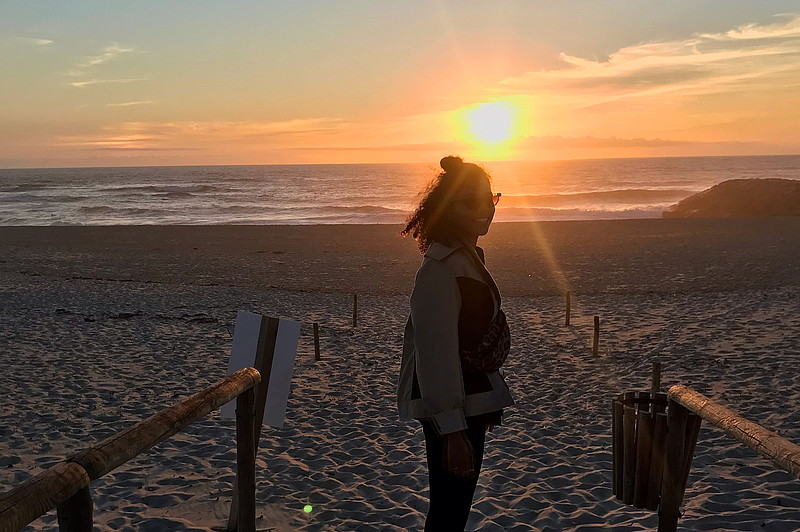 Studentin Sali am Strand und im Hintergrund ist ein Sonnenuntergang 